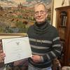 A retired U.S. Army major holds a certificate signed by President Joe Biden.