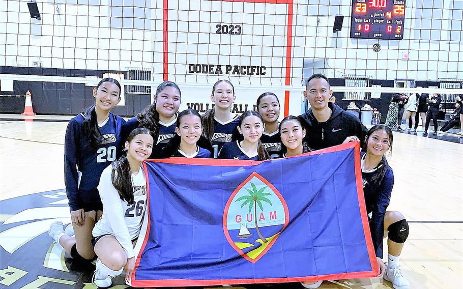 Academy of Our Lady of Guam players and coach Manny Guarin pose with the Guam flag and the Division I tournament championship banner.