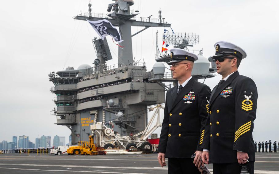 U.S. Navy Master Chief Electronics Technician Anthony Andersen, left, and Master Chief Operations Specialist Dennis Denk man the rails on the flight deck