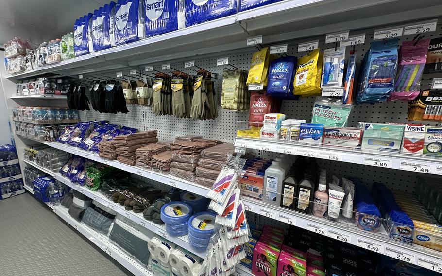 Cases of drinks, gloves, plates and toiletries line shelves in a grocery store layout.