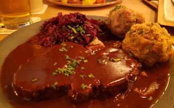 Sweinebraten, a gravy-covered meat dish, with red cabbage and knodels (dumplings)