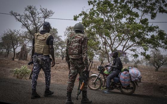 FILE - A police officer and a soldier from Benin stop a motorcyclist at a checkpoint outside Porga, Benin, March 26, 2022. Jihadi fighters who had long operated in Africa’s volatile Sahel region have settled in northwestern Nigeria after crossing from neighboring Benin, a new report said Wednesday, June 19, 2024, the latest trend in the militants' movements to wealthier West African coastal nations. (AP Photo/ Marco Simoncelli, File)