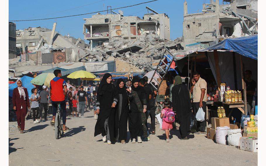 Palestinians gather at a makeshift market set up along a street devastated by Israeli bombardment in the town of Bani Suhayla near Khan Yunis in the southern Gaza Strip on July 17, 2024. (Bashar Taleb/AFP/Getty Images/TNS)