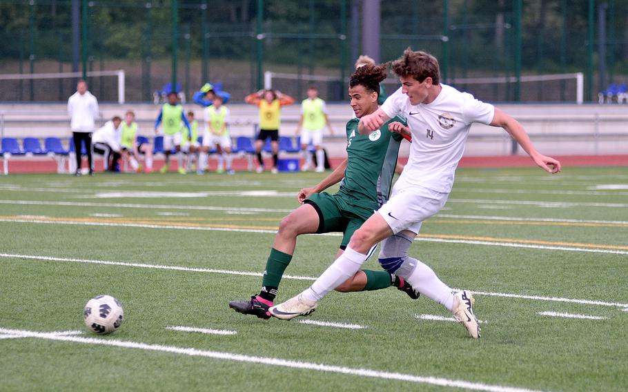 Ramstein striker Jace Monson shoots the ball while holding off SHAPE center back Tycho Kluivert during the Division I final of the DODEA European championships on May 23, 2024, at Ramstein High School on Ramstein Air Base, Germany.