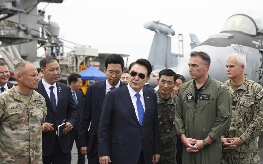 South Korean President Yoon Suk Yeol, center, boards the USS Theodore Roosevelt aircraft carrier at the South Korean naval base in Busan, South Korea, June 25, 2024.