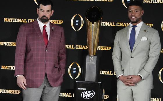 Ohio State head coach Ryan Day, left, and Notre Dame head coach Marcus Freeman pose with the trophy after a news conference ahead of the College Football Playoff national championship game Sunday, Jan. 19, 2025, in Atlanta. The game between Ohio State and Notre Dame will be played on Monday. (AP Photo/Chris Carlson)