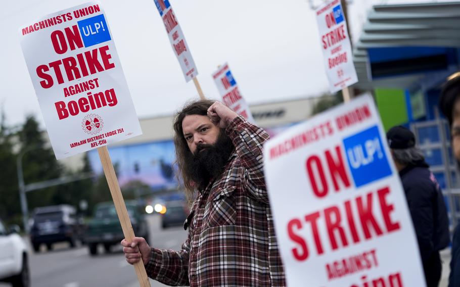 Jacob Bustad, a machinist who has worked for Boeing for 14 years, holds up a fist to passing drivers as union members work the picket line after voting to strike, Sunday, Sept. 15, 2024, in Everett, Wash. 