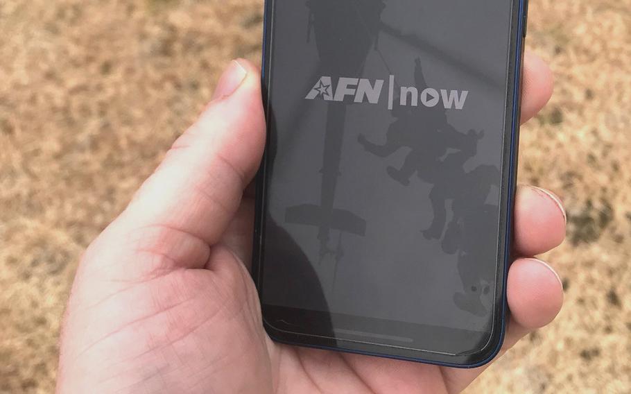 A hand holds a cellphone with the AFN app on it.