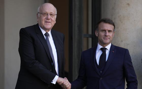 Two men in suits shake hands.