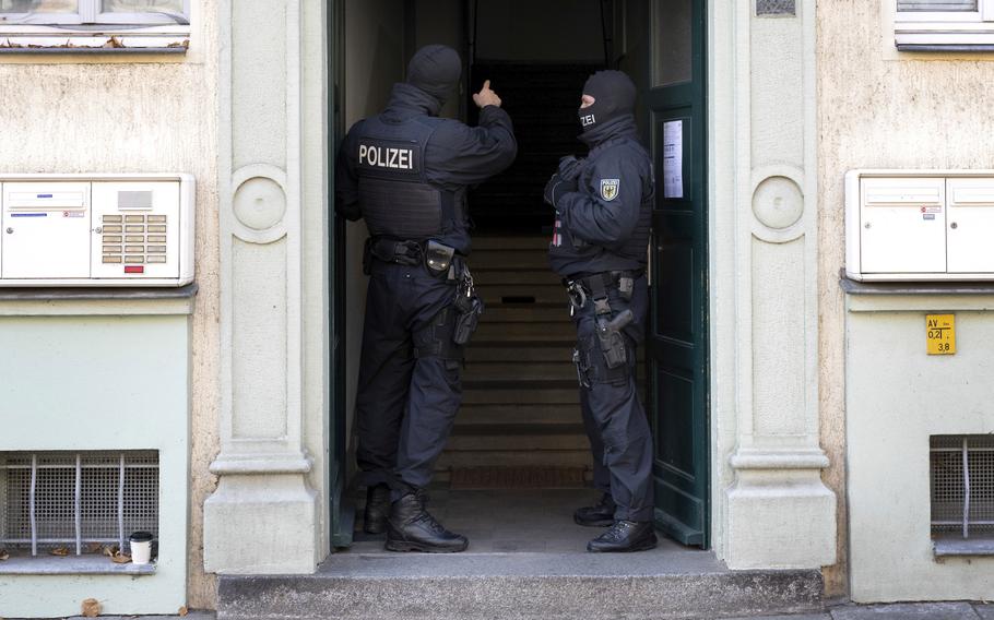 Police officers stand in a building entrance during a raid in Dresden, Germany.