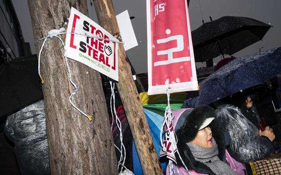 A woman sits behind a "Stop the Steal" sign at a protest against the impeachment and the arrest warrant for South Korean President Yoon Suk Yeol in Seoul on Sunday. MUST CREDIT: Jintak Han/The Washington Post