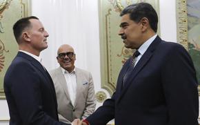 Venezuelan President Nicolas Maduro and U.S. envoy Richard Grenell, both wearing dark suits, shake hands in the presidential palace.