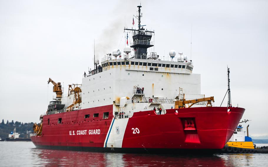 A red and white Coast Guard cutter coasts on a cloudy day.