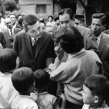 Rep. Daniel K. Inouye (D-Hawaii) — surrounded by Yokoyama villagers and children — listens as one of the villagers addresses him. 