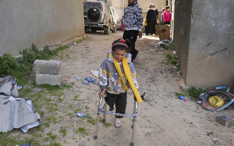 Five-year-old Palestinian amputee Sila Abu Aklan uses a walker to move around outside.