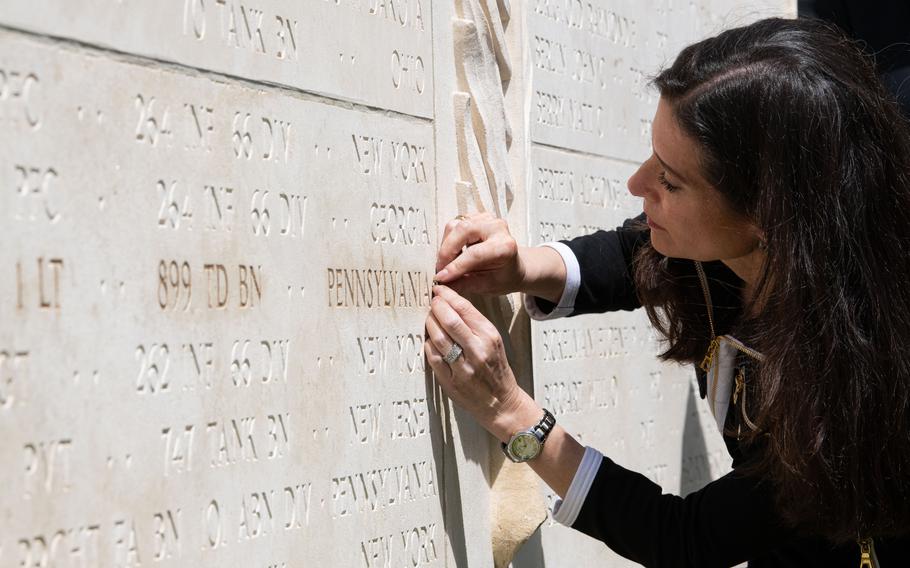 Samantha Baskind inserts a gold rosette into the Wall of the Missing next to the name of 1st Lt. Nathan Baskind at Normandy American Cemetery on June 23, 2024, signifying that her great-uncle’s remains have been found.
