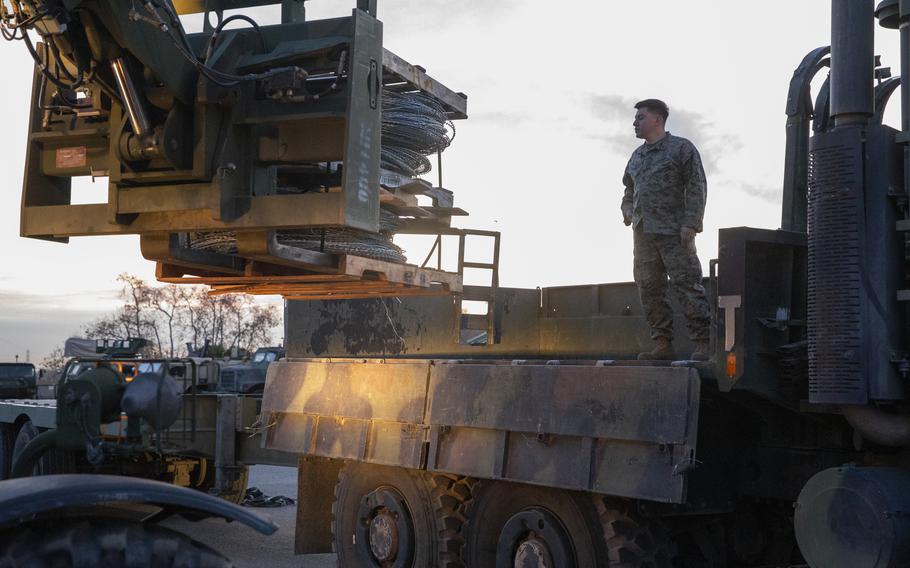 Marine stands on a truck as wire is loaded with a forklift.