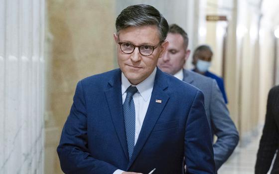 A man in a suit and glasses walks down a hallway in the U.S. Capitol building.