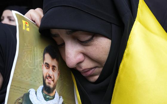 A woman holds a picture of a Hezbollah member who was killed on Wednesday when a handheld device exploded, during his funeral procession in the southern suburbs of Beirut, Thursday, Sept. 19, 2024. (AP Photo/Hussein Malla)