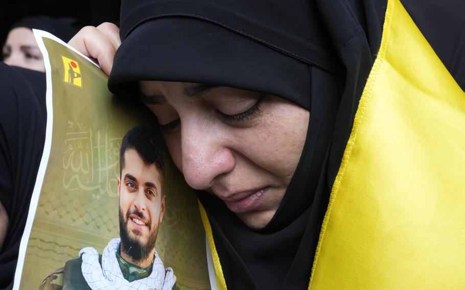 A woman holds a picture of a man who was killed in a pager attack in Lebanon