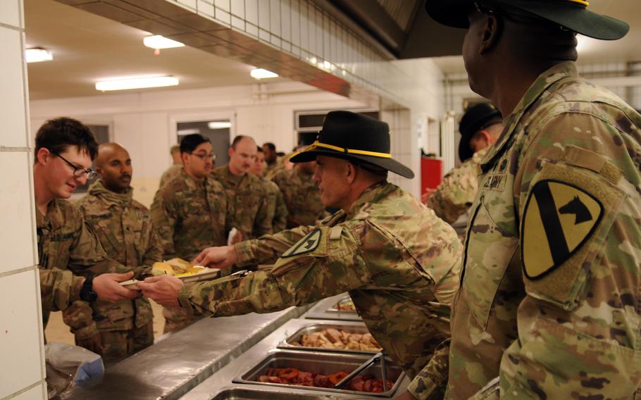 Command Sgt. Maj. James Light, the senior enlisted advisor for the 1st Armored Brigade Combat Team, 1st Cavalry Division, hands tray of food to a soldier