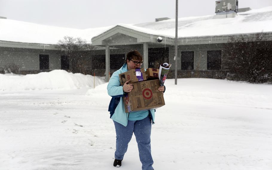 A woman carries boxes from her office after being fired from her federal job.