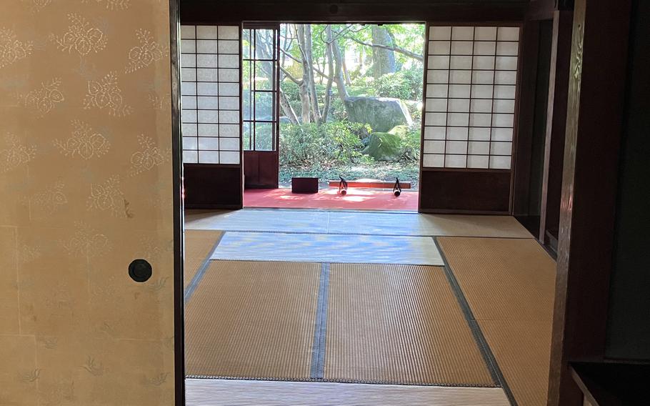 Sliding doors open to reveal a room containing a tatami mat, screens with paper panels and a narrow, enclosed porch.