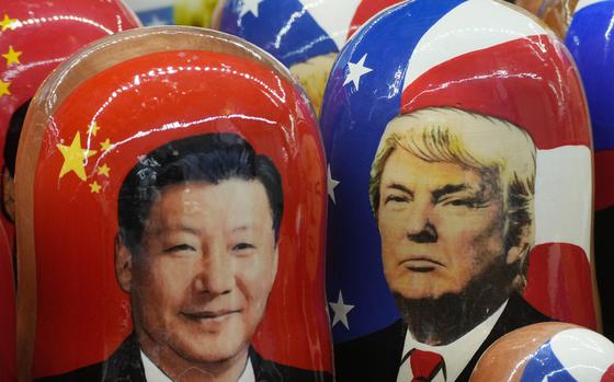 The likenesses of Xi Jinping and Donald Trump against their respective national flags on shiny doll surface.