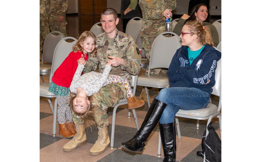 Soldier embraces his playful daughters