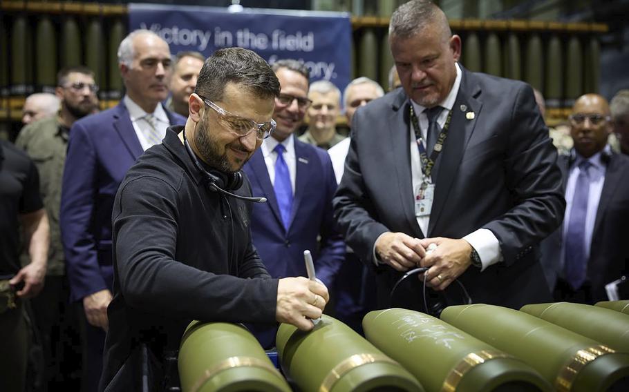 Volodymyr Zelenskyy, left, is watched by Rich Hansen, the commander’s representative for the Scranton Army Ammunition Plant.