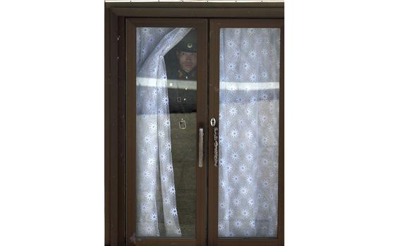 Demilitarized Zone, South Korea, April 17, 2002: A North Korean military officer takes a peek from the North Korean recreation building at the truce village of Panmunjom, north of Seoul.

META TAGS: Korean War; armistice; DMZ; 