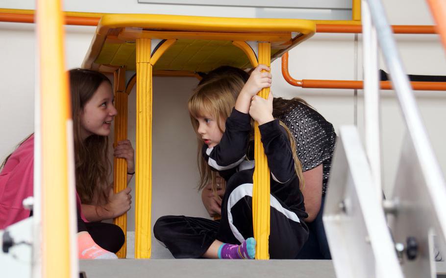 A woman and two young girls sit under a table.