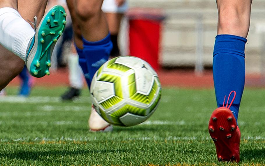 Players battle for a soccer ball.