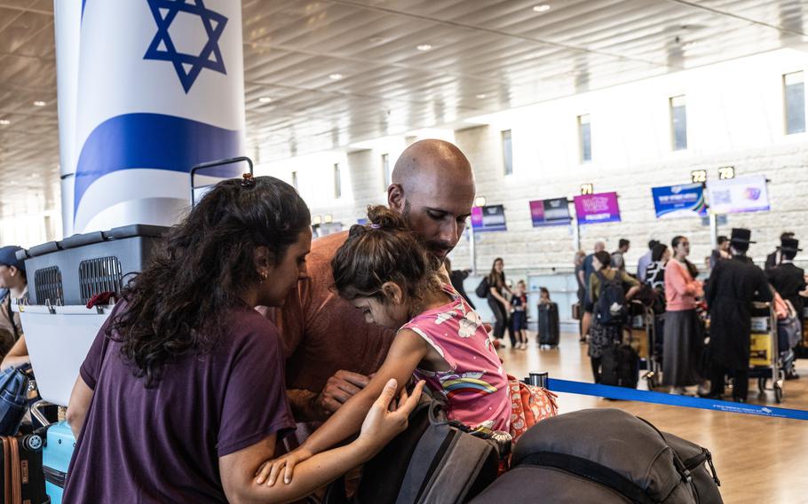 Enav and Ariel Graff embrace their daughter Luna, 3, as they wait for a flight to Portugal. 