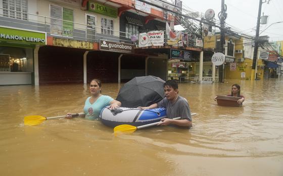 Residents use rubber paddles from a toy boat as they wade along a flooded street caused by heavy rains from Tropical Storm Yagi, on Monday, Sept. 2, 2024, in Cainta, Rizal province, Philippines. (AP Photo/Aaron Favila)