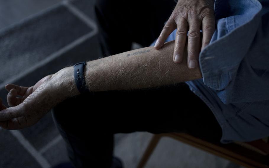 Naftali Fürst pushes up a shirtsleeve to reveal numbers tattooed on his arm.