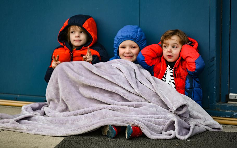 Kids bundle up under a blanket together