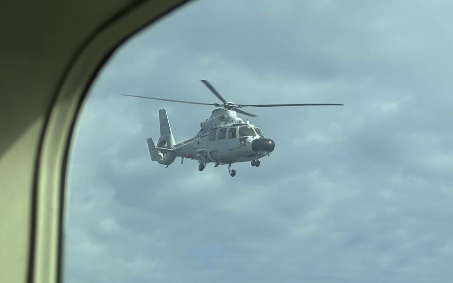 A military helicopter is seen through the window of another aircraft.