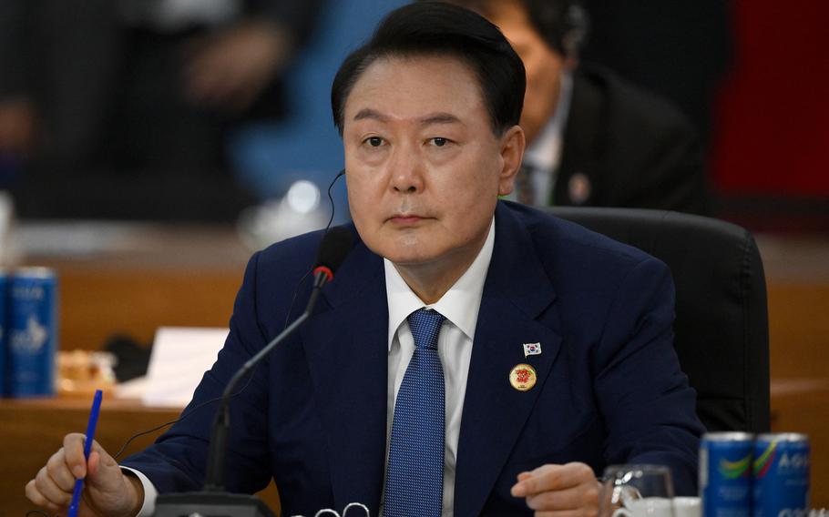 South Korean President Yoon Suk Yeol seated and in front of a microphone.