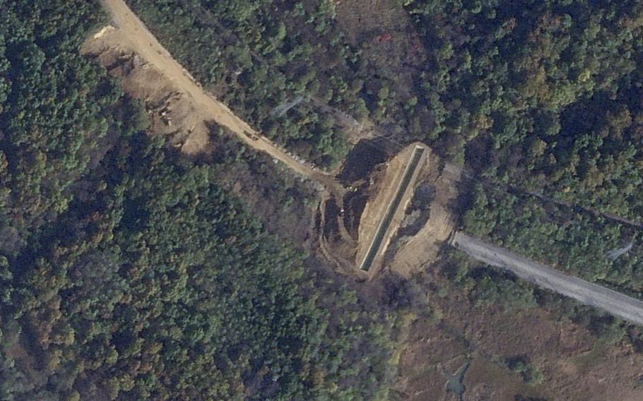 A trench surrounded by trees is dug along a road in the Demilitarized Zone.