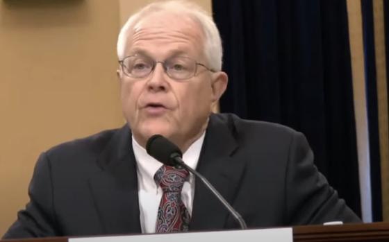 A man in a dark suit and glasses speaks into a microphone during a congressional hearing at the U.S. Capitol.