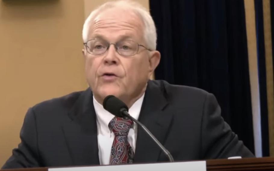 A man in a dark suit and glasses speaks into a microphone during a congressional hearing at the U.S. Capitol.