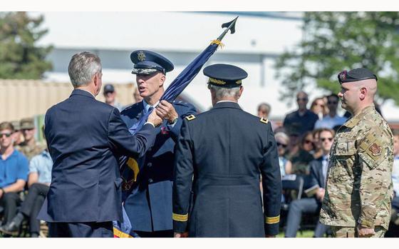Idaho Gov. Brad Little hands over the National Guard flag from outgoing commander, Michael J. Garshak, to the incoming commander, Maj. Gen. Timothy J. Donnellan, during a ceremony at Gowen Field.