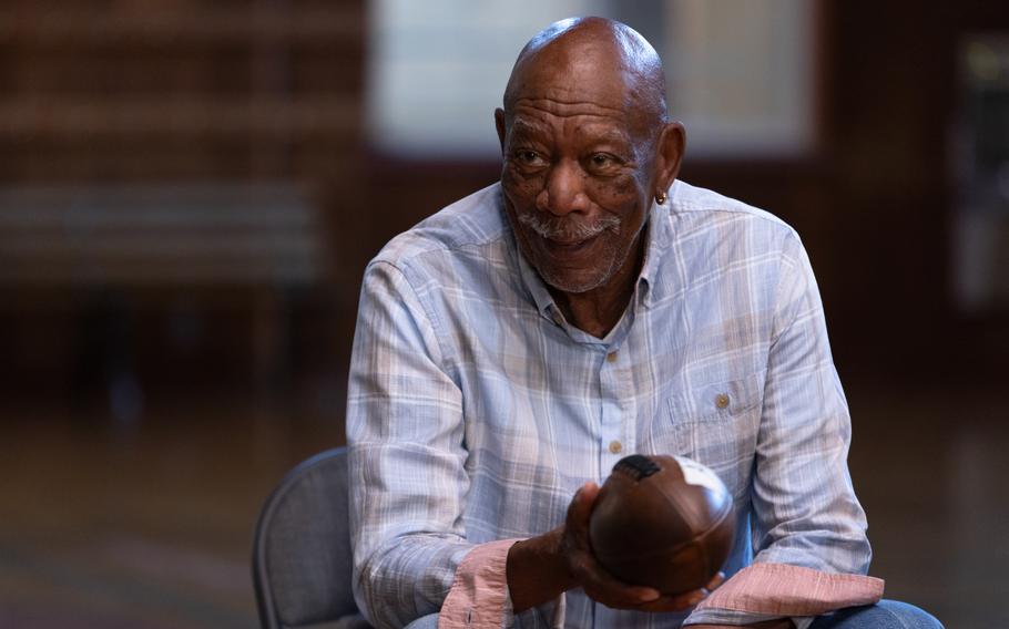 Morgan Freeman seated and holding a football.