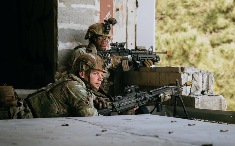 U.S. Army paratroopers hold rifles and crouch in a building during training in Greece.