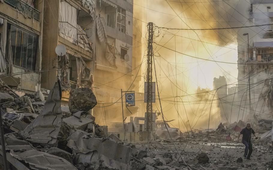 A man runs for cover as a smoke raises in the background following an Israeli airstrike in Dahiyeh, Beirut, Lebanon, Friday, Oct. 4, 2024.