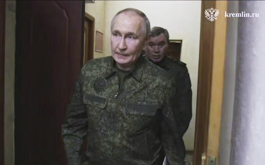 Vladimir Putin in military fatigues walking through a doorway.