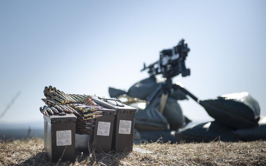 Rounds of ammos rest next to a machine gun.