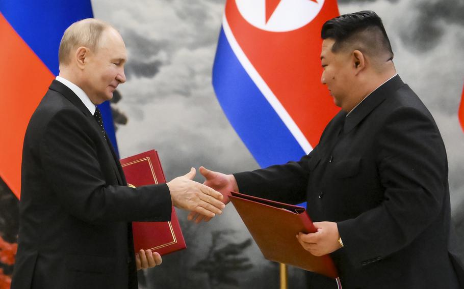 Russian President Vladimir Putin, left, and North Korean leader Kim Jong Un exchange documents during a signing ceremony in Pyongyang, North Korea, on June 19, 2024.