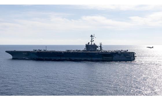 The USS Harry S. Truman underway at sea as a fighter jet prepares to land on deck.